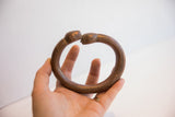 The substantial form and aged patina of the antique snake cuff shown in hand.