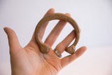 Collectible African copper cuff held in a palm, showing its scale and incised details.