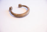 Etched linear details and aged patina on the curved body of an antique African bracelet.