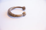 The curved form of a handmade African snake cuff bracelet with an antique brass patina.