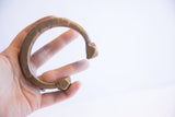 Antique African cuff bracelet held in hand, displaying its substantial form and aged patina.