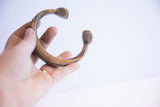 Antique African snake cuff bracelet held in hand, showing its scale and aged patina.