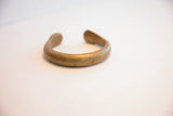 Smooth, thick band and open design of the antique African brass cuff.