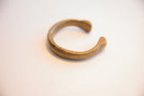 A three-quarter view of the antique African snake cuff's simple, curved form.