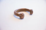 The hand-formed terminal and aged copper patina of an antique African bracelet.