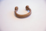 Aged copper cuff bracelet showing its thick, curved band and open design.