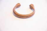 The open C-shape of the antique African cuff with its warm, aged patina.