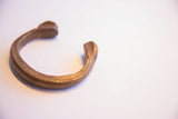 Side view of the antique African cuff showing its open C-shape and warm patina.