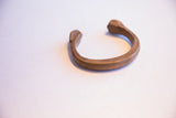 The sculptural C-shape and warm bronze patina of the antique African cuff.