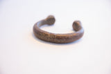 Angled profile of an antique African snake cuff highlighting its dark aged metal patina.