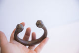 The antique African snake cuff held in hand to show its scale and aged metal patina.
