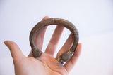 Antique African snake cuff bracelet held in a palm to show its scale and form.