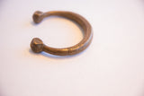 The C-shaped form and aged patina of an antique African snake cuff bracelet.