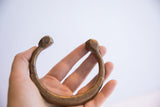 Antique African snake cuff bracelet held in hand showing its solid, sculptural form.