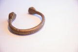 The aged metal patina and solid, curved form of the antique snake cuff.