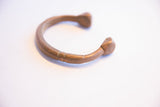 The open form and aged metal patina of the antique African snake cuff bracelet.