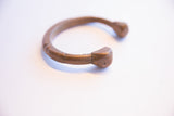 The stylized terminals and aged copper-like patina of an antique African cuff bracelet.
