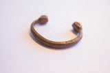 Aged copper patina and hand-etched details on the curved band of a collectible African cuff.