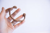 Antique African copper snake cuff held to show its curved shape and size.
