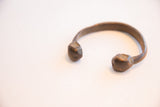 Close view of the faceted, hand-forged ends of an antique snake cuff.