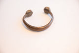 The open C-shape of the antique handmade African cuff showing its aged patina.
