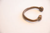 Profile view of an antique African cuff showing its open, curved form.