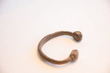Profile view of an antique African snake cuff showing its open design and aged patina.