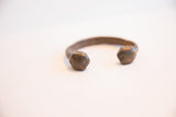 Aged brown patina on the faceted ends of an antique African cuff.