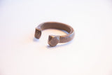 The faceted geometric ends and dark aged patina of an antique African cuff.