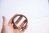 Antique African cuff bracelet held in hand, displaying its substantial form and aged patina.