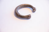 The open shape and aged, textured surface of an antique African snake cuff bracelet.