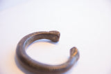 The faceted terminal and aged metal patina on an antique African snake cuff.