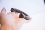 Antique snake cuff bracelet held in a palm, showing its size and smooth, dark surface.