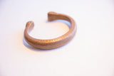 The warm patina and hand-formed shape of an antique African copper cuff bracelet.