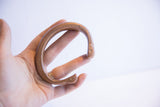 Antique copper snake cuff bracelet held to demonstrate its size and C-shape profile.