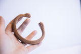 Antique copper snake cuff bracelet held to display its size and aged patina.