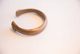 Side profile of the antique copper bracelet highlighting its smooth, open curve.
