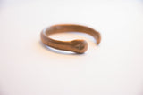 Close-up of the antique copper cuff's terminal revealing hand-worked markings and texture.
