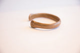View of the antique copper bracelet's smooth curve and open end.