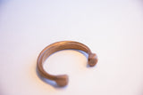 Angled profile of the antique copper cuff showing its aged patina and form.