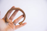 A hand holds the antique copper cuff bracelet, illustrating its size and warm patina.