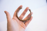 Antique snake cuff bracelet with etched details held in hand to show its scale.
