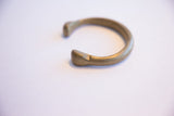 The thick, rounded ends and aged patina of an antique African bronze bracelet.
