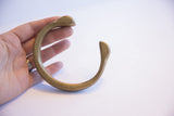 Antique bronze snake cuff bracelet held in a hand to demonstrate its size and form.