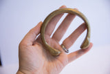 The antique African bronze bracelet held in hand, displaying its substantial curved form.