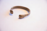 View of the open cuff and rounded terminals on the antique bronze bracelet.