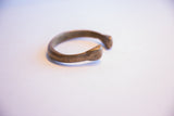 The smooth, curved form and open ends of the antique African bronze cuff.