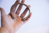 Antique African bronze snake cuff held in hand, showing its overall size and circular form.