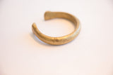 Angled perspective of an antique bronze cuff, highlighting its open shape and aged texture.