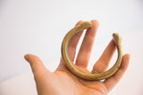 A hand holds the antique bronze cuff showing its substantial size and curved shape.